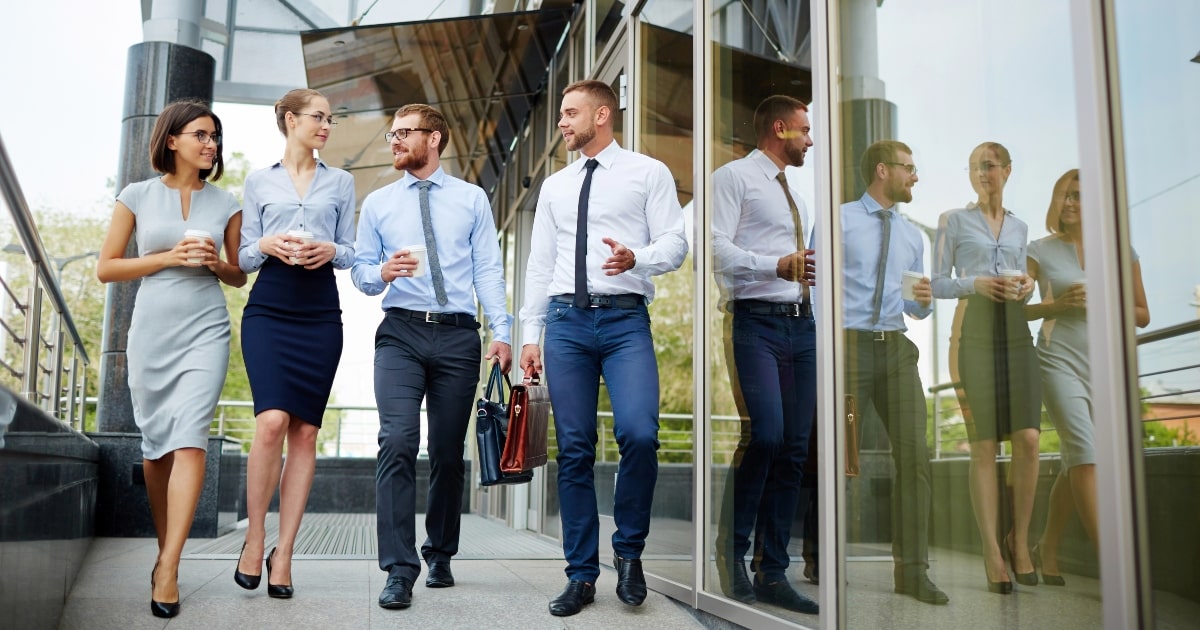 Four coworkers dressed in business attire, walking outside an office, illustrating commercial property leasing.